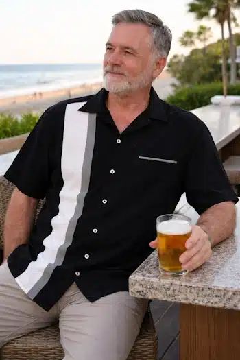 Man relaxing at the beach wearing classic retro style bowling shirt